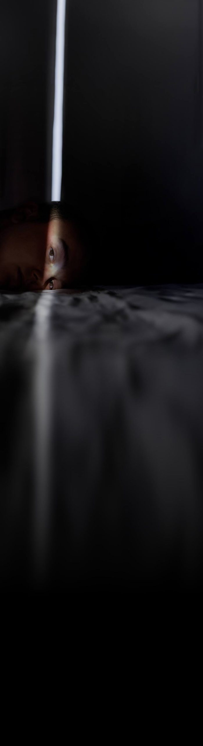 Photographie de Lucae Regourd : un visage allongé traversé par un rayon de lumière vertical